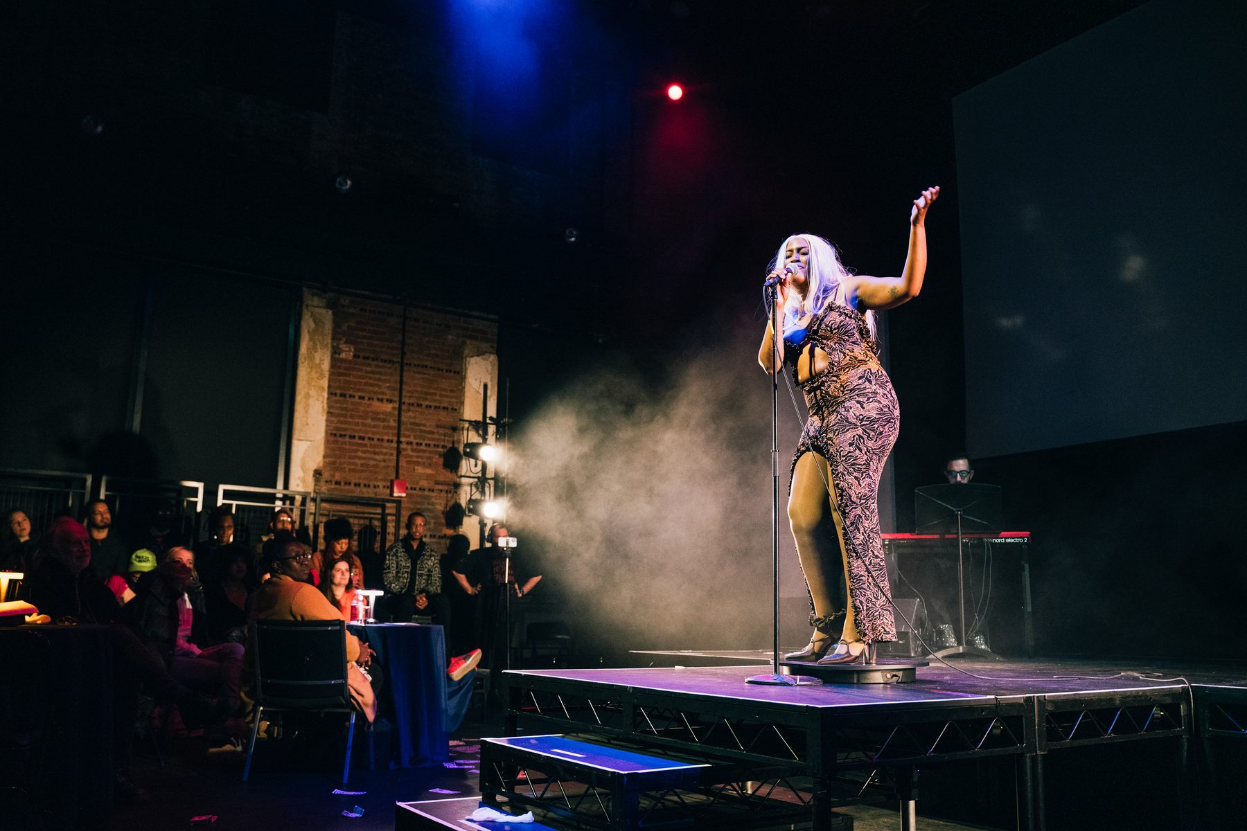 Mandy Harris Williams performing Critique Cabaret — full stage, audience, haze, and theatrical lighting at LINT