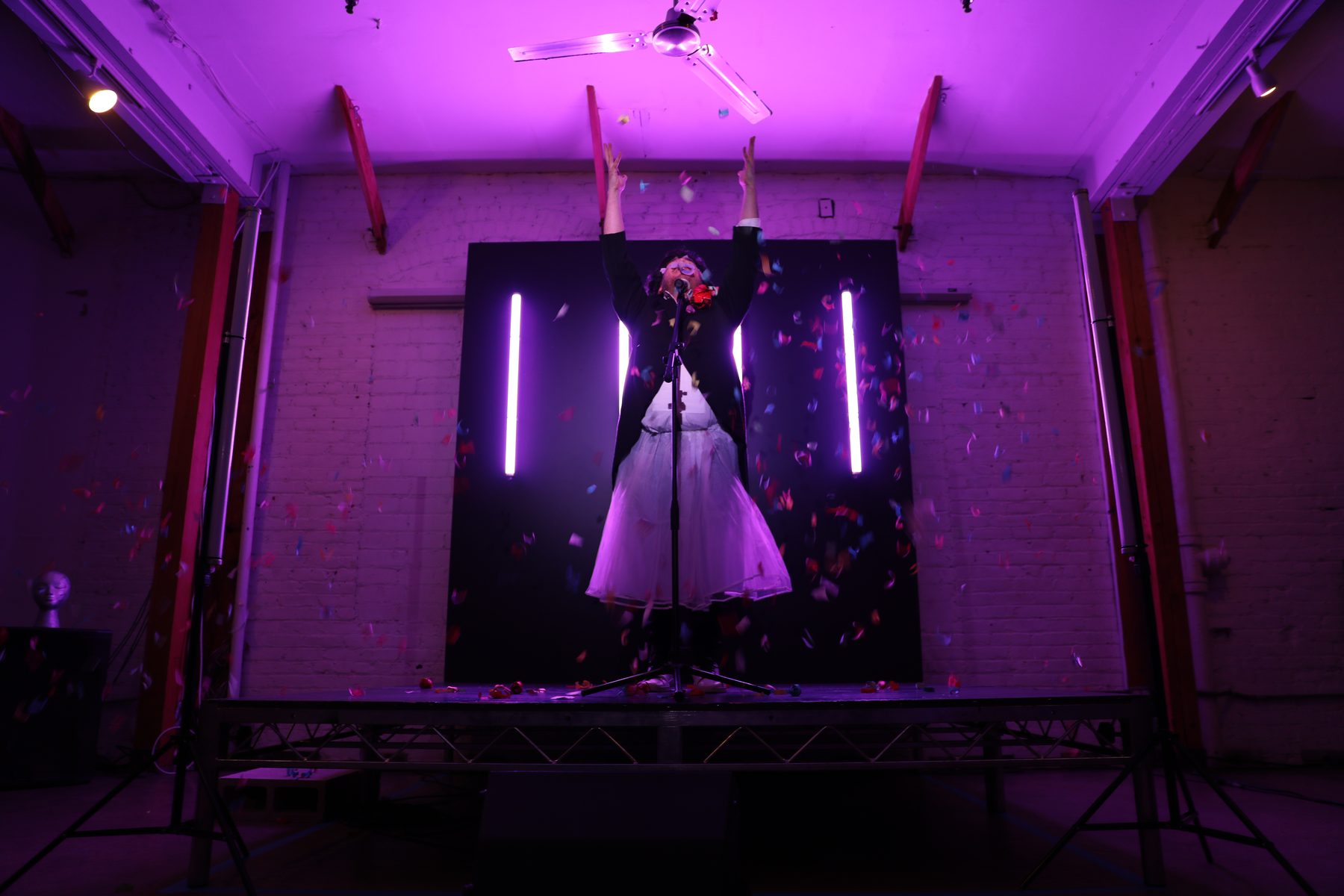 Bottoming for Jesus performance — purple theatrical lighting, confetti, triumphant moment on stage