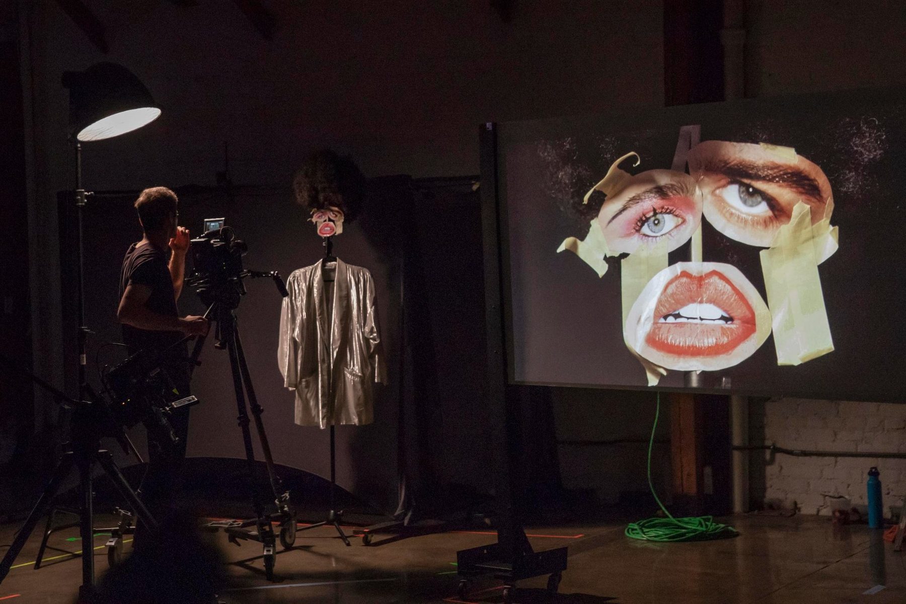 Camera operator filming inside LINT — projection, mannequin, production in progress